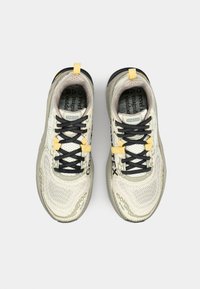 Lette kremfargede og grå sneakers med svarte snørebånd, strukturert mesh-overdel, gule detaljer og en slitesterk gummisåle.