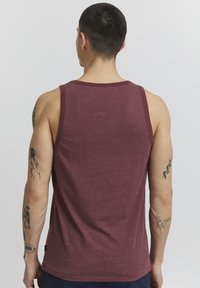 Maronfarbener Tanktop mit geripptem Halsausschnitt und Armöffnungen, das eine glatte Textur und eine normale Passform aufweist. Von hinten gezeigt.