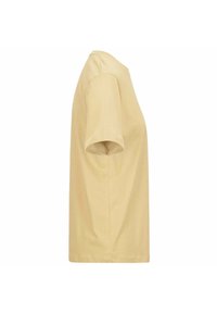 Camiseta de algodón de manga corta y corte holgado en color amarillo pálido, con cuello redondo y textura suave, sin patrones ni adornos visibles.