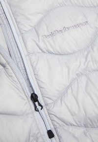 Lichtgrijze donsjas met een doorgestikt ontwerp, rits aan de voorkant met contrasterende zwarte details en het "Peak Performance"-logo in witte stiksel.