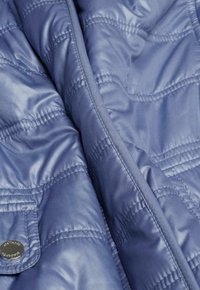 Blau gepolsterte Jacke mit gestepptem Muster, glänzender Textur, detaillierten Nähten und einem metallischen Knopfverschluss an der Fronttasche.