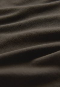 Donkerbruin stof met een zachte textuur, met subtiele plooien die diepte creëren. Het weefsel is glad en egaal, wat duidt op een materiaal van hoge kwaliteit.