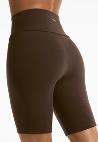 Brown high-waisted bicycle shorts made of stretch fabric, featuring a smooth texture and a seamless design with no visible hardware.