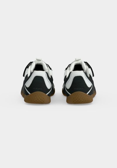 Paire de baskets noir et blanc avec semelles marron vues de dos, avec des détails en mesh et cuir et une languette sur chaque talon.