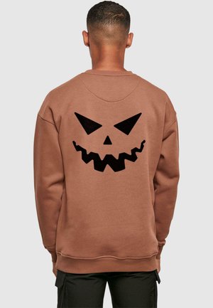 Brun sweatshirt med et stort sort græskar ansigt grafisk tryk på bagsiden. Lavet af en bomuldsblanding, den har en afslappet pasform og ribbede manchetter.