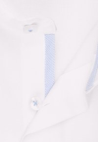 Weißer Stoff mit strukturierter Webart, versehen mit einem Knopfverschluss und einem blauen Kreuzstich sowie hellblauen Akzenten.