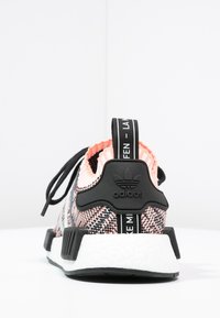 Rear view of Adidas sneaker with pink and black knit upper, black heel tab, white sole, and black pull tab with white text.