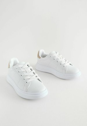 Adidași albi cu o textură netedă, cu șireturi albe, o talpă căptușită și un accent bej deschis la călcâi. Design simplu, fără modele.