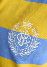 Material dungat în dungi galbene și albastre, cu un blazon brodat alb ce prezintă o coroană, litere împletite și o coroană de lauri.