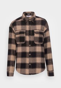 Rutig skjorta i tan och svart, tillverkad av mjukt tyg, med knäppning framtill, två bröstfickor och rundad nederkant.