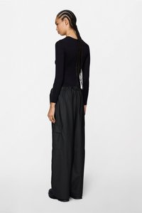 Μαύρο πουκάμισο με μακριά μανίκια συνδυασμένο με μαύρο παντελόνι καμπάνα με ελαστική μέση και πλαϊνές τσέπες, εμφανιζόμενο από πίσω.