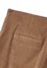 Brown corduroy fabric featuring a vertical ribbed texture, with a single back pocket and clean stitching detail.