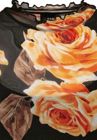 Crni mrežasti materijal s velikim narančastim i žutim ružama te smešnim lišćem. Obrađena ovratnica s volanima.