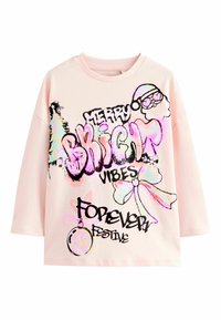 Tricou roz deschis cu mânecă lungă, având text în stil graffiti negru și grafică colorată, care include designuri cu Moș Crăciun, globuri și fundițe.