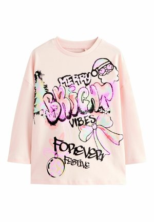 Vaaleanpunainen pitkähiha t-paita, jossa on mustaa graffitotyylistä tekstiä ja värikkäitä grafiikoita, mukaan lukien joulupukki, koriste ja nauha -kuvioita.