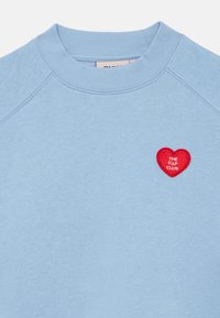 Ανοιχτό μπλε φούτερ λαιμόκοψης με ριμπ στο κολάρο και μικρό κόκκινο κεντητό καρδιάκι με την επιγραφή "THE V.I.P CLUB" στο αριστερό μέρος του στήθους.