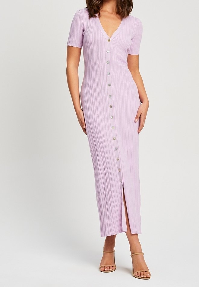 Femme portant une robe midi boutonnée lilas côtelée, à manches courtes et fente frontale, associée à des talons à bride cheville couleur nude.