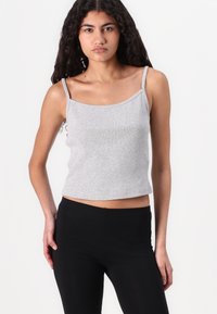 Grå ribbet tanktop med tynde stropper, med en cropped pasform og tætsiddende design, parret med sorte leggings. Enkel og alsidig stil.
