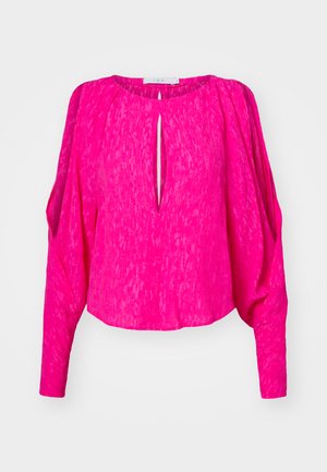 Rosa, teksturert bluse med lange ermer og nøkkelhull-dekning. Har samlet detaljer på ermene og en kortere hem.