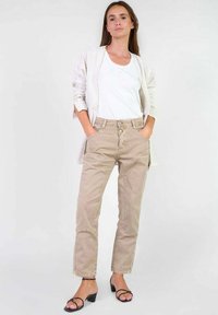 Beige katoenen broek met een rechte snit, voorzien van twee vo pockets, knoopsluiting en een witte tanktop gecombineerd met een gestreepte cardigan.