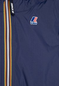 Giacca a vento navy realizzata in materiale leggero. Presenta una zip frontale con strisce multicolori e un logo K-WAY sul petto.