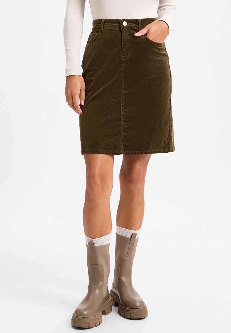 Olive green corduroy skirt with front pockets and a button closure, paired with knee-high brown rubber boots and white ribbed socks.