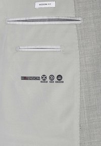 Wnętrze szarego garnituru z etykietą "MODERN FIT", dwoma wewnętrznymi kieszeniami oraz symbolami H-XTENSION oznaczającymi komfortowy stretch i wydajność.