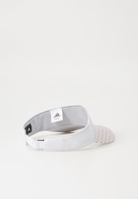 Fehér napellenző, mintás rózsaszín csúccsal. Könnyű anyagból készült, állítható pánttal rendelkezik, és az Adidas logója az belsejében található.
