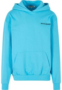 Sudadera con capucha de color azul claro, fabricada en una mezcla de algodón, que presenta un bolsillo frontal y el texto negro "9N1M SENSE" en el área del pecho izquierdo.