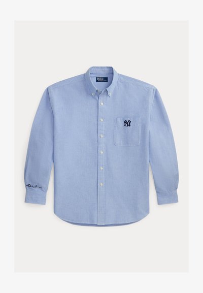 Hellblaues Langarmhemd mit Knopfleiste, Brusttasche bestickt mit dunkelblauem NY-Logo und Signatur am linken Manschettenband.