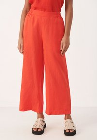 Wijde broek in fel oranje linnen met een elastische tailleband. Gekocht met beige sandalen met een geweven ontwerp en dikke zwarte zolen.