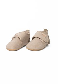 Beige stoffen schoenen met een gestructureerd oppervlak, klittenbandsluiting en tan rubberen zolen, ontworpen voor comfort en gebruiksgemak.