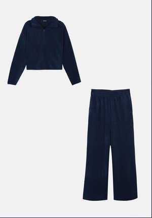 Mørkeblå fleece loungewear sæt med langærmet halv-zip trøje og brede elastiske bukser på hvid baggrund.
