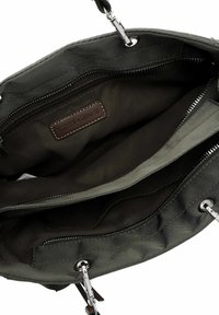 Zelená látková kabelka se stříbrným kováním, děleným vnitřkem a hnědou štítkovou etiketou s logem. Má tmavé, hladké podšívky a přihrádky na zip.