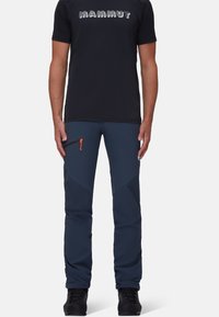 Pantaloni outdoor blu navy con accenti scuri a contrasto, tasche con zip e cintura elastica. Realizzati in tessuto resistente alle intemperie.