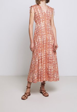 Robe midi à motifs rouges et crème avec un décolleté en V, des bretelles à nouer et une jupe fluide. Portée avec des sandales à lanières marron.