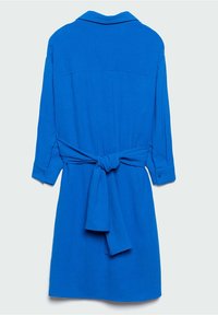 Robe bleu vif à manches longues avec col et nœud à la taille, vue de dos sur un fond clair.