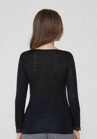Langärmliges, eng anliegendes Oberteil in Schwarz, aus leichtem Material, mit filigranen Spitze-Akzenten an den Ärmelbündchen und einem runden Ausschnitt.