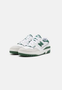 Sneakers bianchi e verdi con una tomaia in suede e pelle testurizzata, dotate di una suola imbottita, lacci classici e un logo laterale.