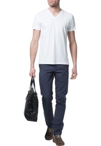 Hvid v-hals t-shirt, marineblå slim-fit bukser, brune ruskindssko. Bærer en sort læder tote taske. Enkel, afslappet påklædning.