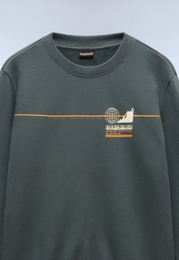 Felpa grigio scuro con scollatura a costine, caratterizzata da una grafica color crema di un globo e una montagna, accentuata da strisce orizzontali arancioni.