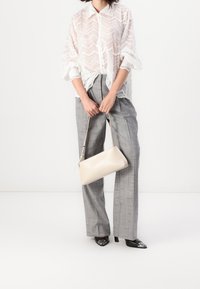 White lace blouse with scalloped edges, gray checked wide-leg trousers, and a beige rectangular handbag, paired with black pointed-toe heels.