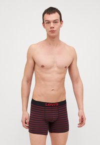 Svarta och röda randiga kalsonger i mjukt tyg, med en svart midja där "Levi's"-logotypen är tydligt visad.