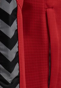 Black and white chevron patterned fabric next to red textured fabric with a red seam in between.