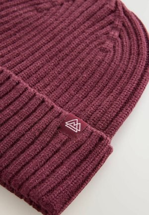 Mørkerød strikket hue med ribbet tekstur, der har et lille hvidt logo-patch på siden. Blødt, varmt materiale med design til opsmøring.