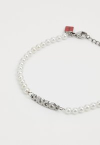 Pärlhalsband med metallisk "HUGO" berlock. Har vita pärlor och silverfärgad hårdvara, med ett lås för säker användning.