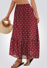 Jupe maxi florale bordeaux en tissu léger, avec un design à volants et une taille élastique. Associé à un sac en osier et des sandales.