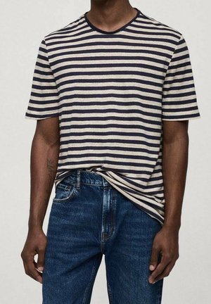 Camiseta de rayas en colores azul marino y beige, de manga corta y cuello redondo. Combinada con jeans de mezclilla, mostrando un look casual.