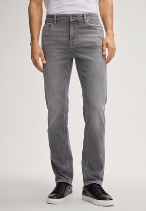Graue Denim-Jeans mit geradem Bein, fünf Taschen und dezenten Ausbleichungen. Kombiniert mit schwarzen Sneakern, insgesamt glatte Textur.
