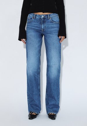 Jasnoniebieskie jeansy o prostych nogawkach z efektem sprania, z pięcioma kieszeniami i zapięciem na guzik. Tkanina ma klasyczną teksturę dżinsu.